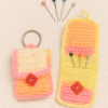 A handmade Crochet Hijab Pin Organizer in pink, orange, and yellow yarn, showing both a closed pouch with a keychain and an open pouch holding several colorful hijab pins.