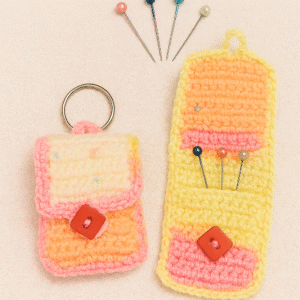 A handmade Crochet Hijab Pin Organizer in pink, orange, and yellow yarn, showing both a closed pouch with a keychain and an open pouch holding several colorful hijab pins.