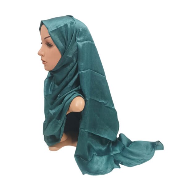 Teal embossed Muna satin hijab styled on a mannequin, highlighting the smooth satin finish and subtle textured pattern.