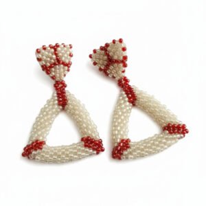 A pair of handcrafted, geometric triangle drop earrings made from cream and crimson red beads, shown on a white background.