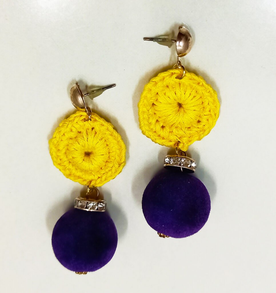 Handmade Velvet Sun dangle earrings featuring a yellow crochet circular disc and a purple velvet ball with a rhinestone spacer on a white background.