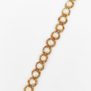 A handcrafted Golden Halo Pearl bracelet featuring ivory pearls surrounded by gold-toned bead halos with a lobster clasp on a white background.