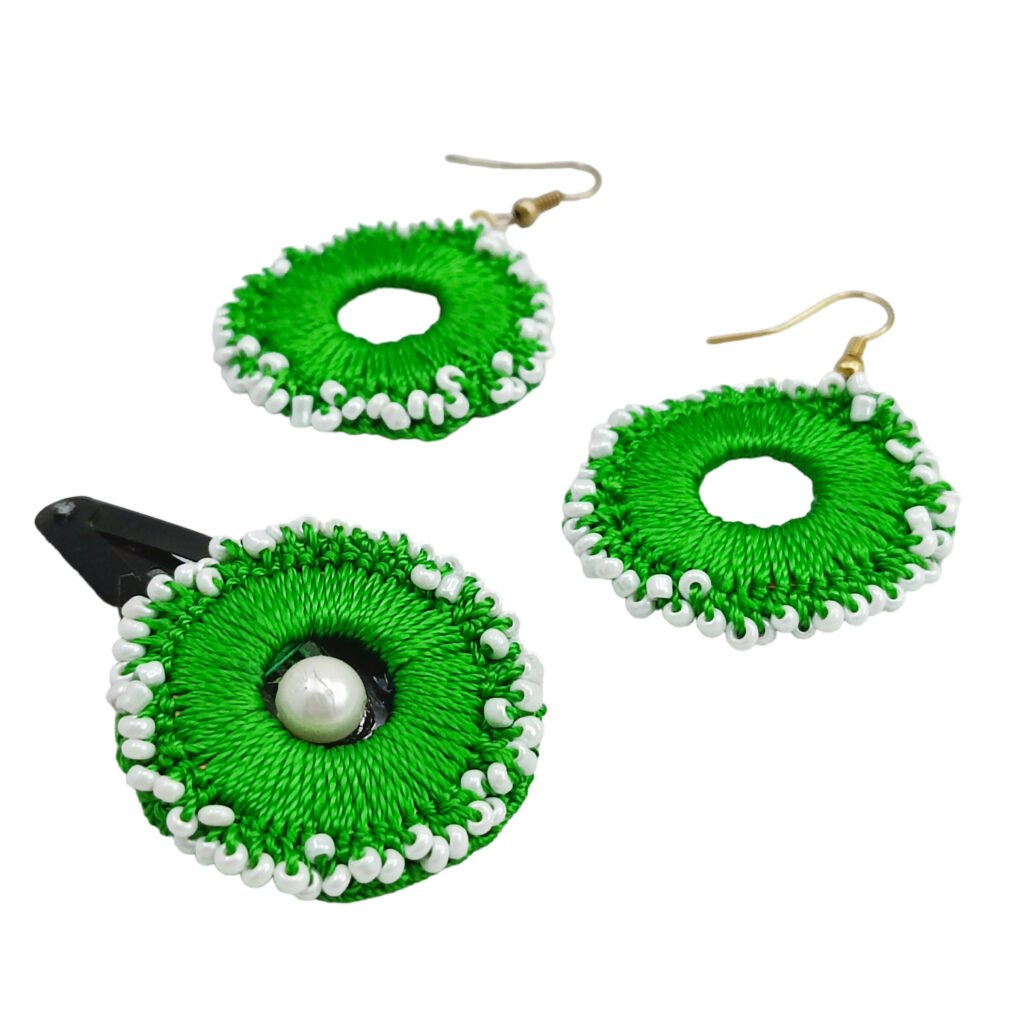 A coordinated handmade Eva Earring Combo Set featuring a matching pair of circular woven crochet hanging earrings and a circular snap hair clip adorned with an inset white pearl.